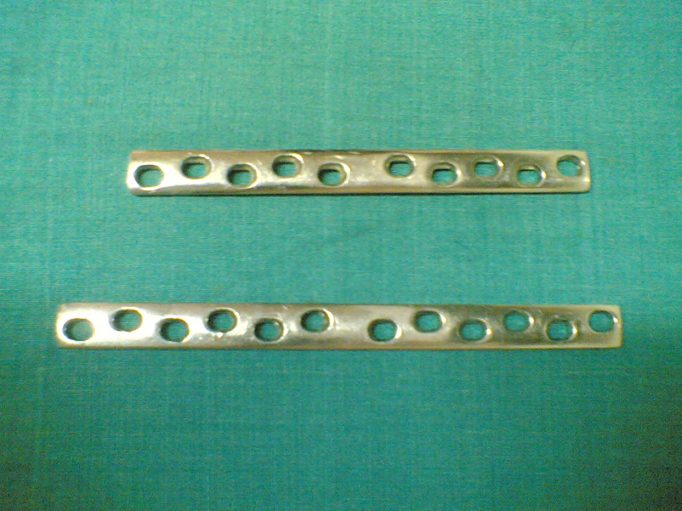 Figure 4. A broad dynamic compression plate (DCP); the oval inclined holes drive axial compression when a screw is placed eccentrically. Source: Netha Hussain, via Wikimedia Commons, CC BY-SA 3.0.